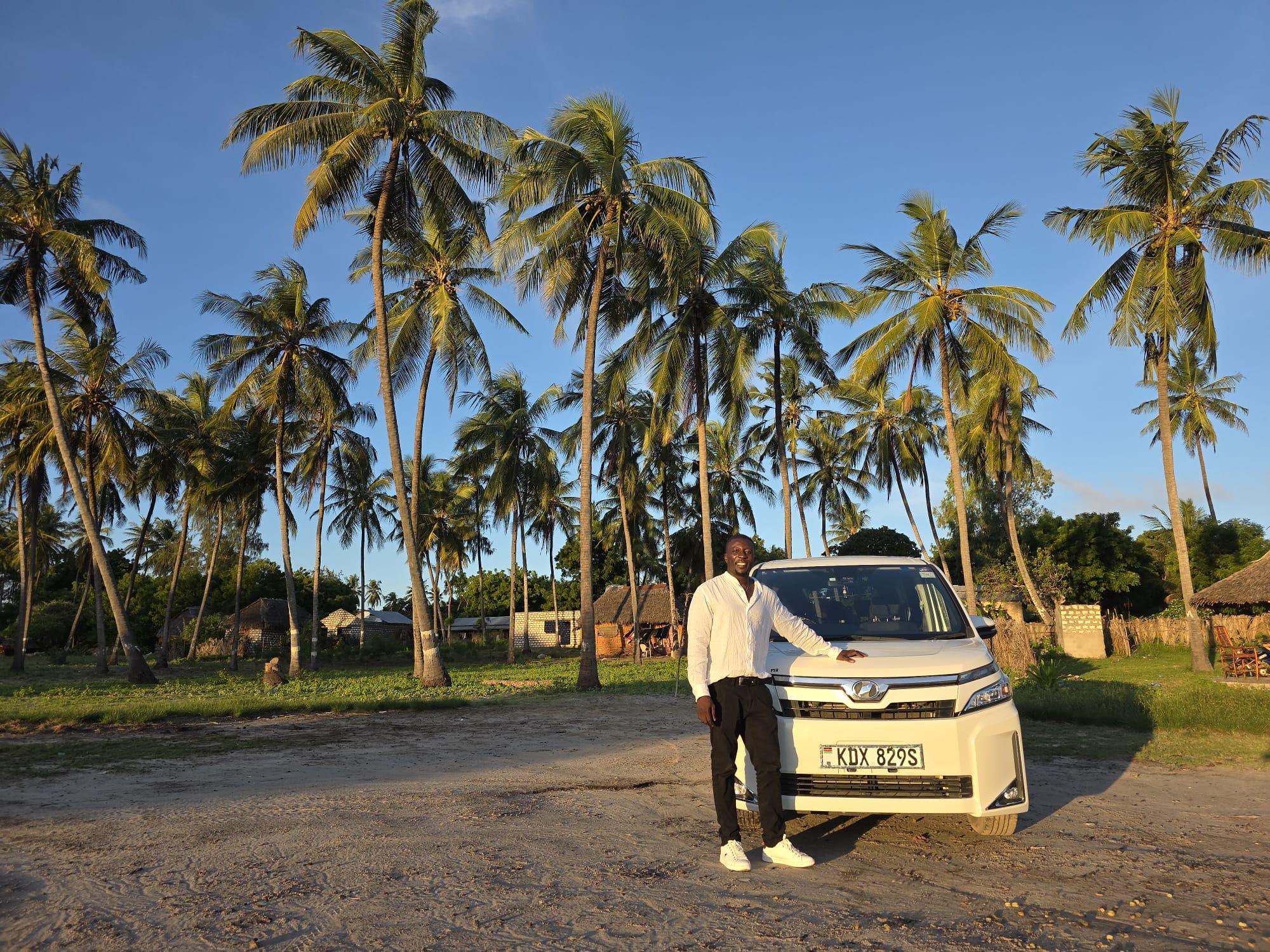 Autista accanto al van Toyota per i transfer, tra le palme di una spiaggia in Kenya al tramonto